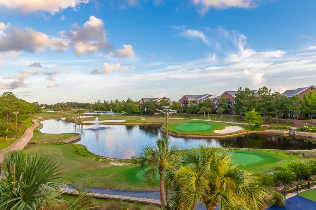 Beautiful aerial view of a golf course with a pond and palm trees.