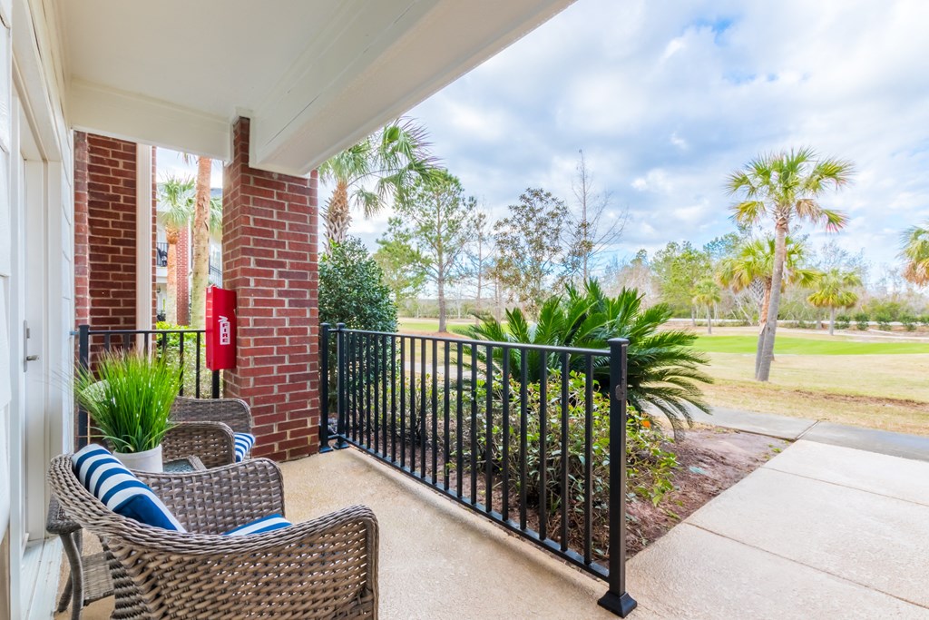 a patio with two chairs and a black railing on a porch