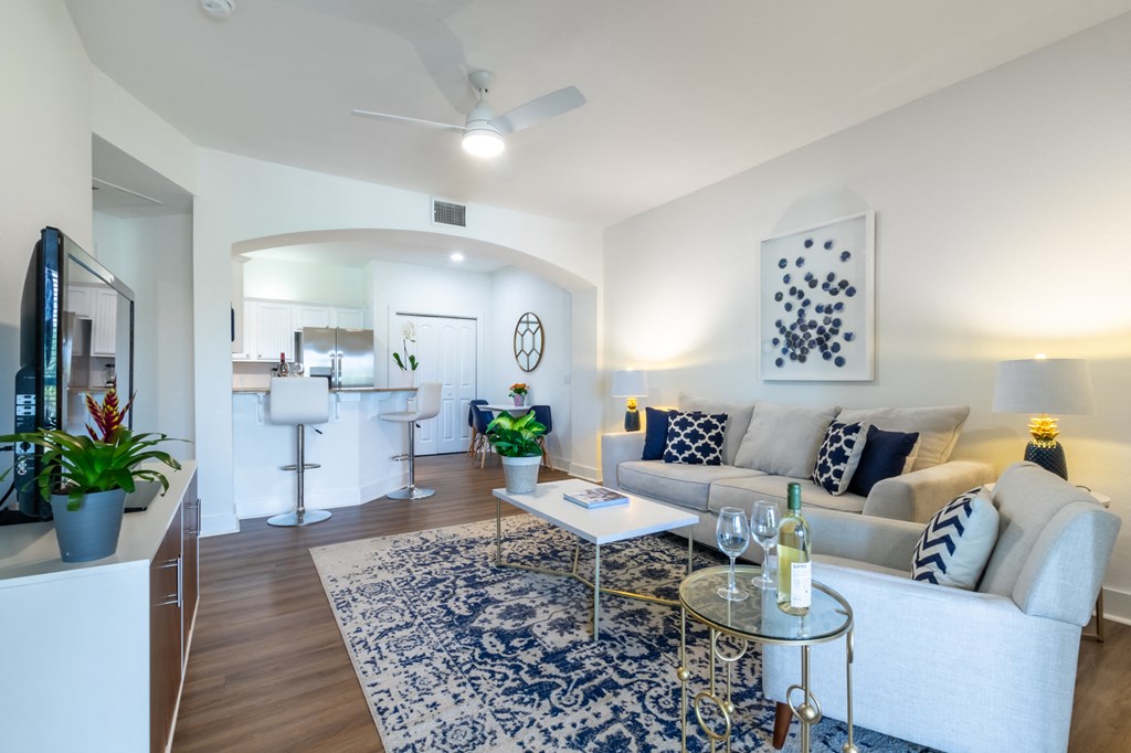A living room with a white couch and a glass coffee table.