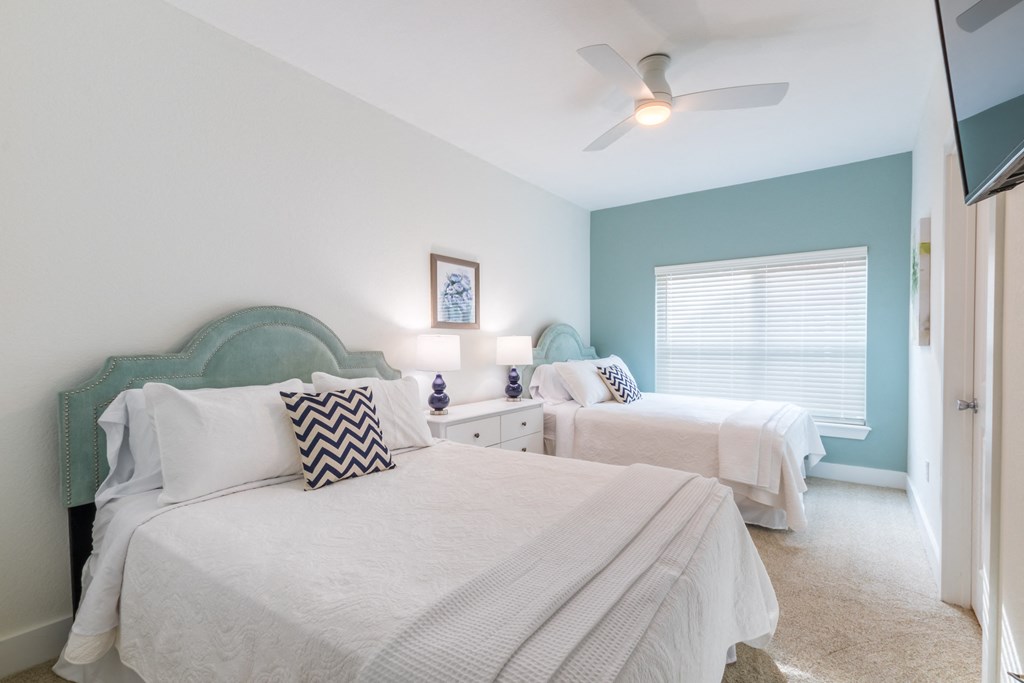 a bedroom with two beds and a ceiling fan