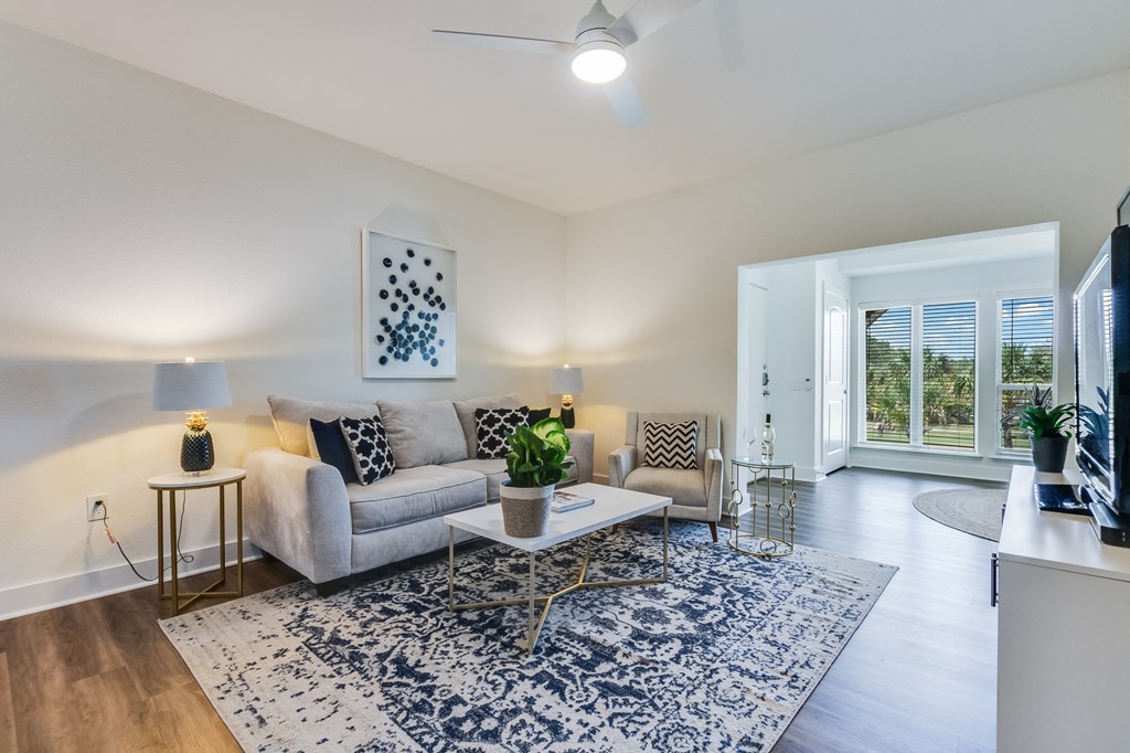 A living room with a grey couch, a white coffee table, and a blue and white rug.