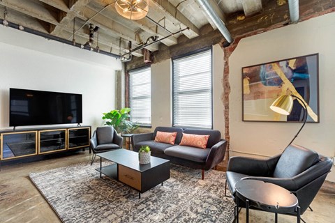 A living room with a black leather couch and a wooden coffee table.