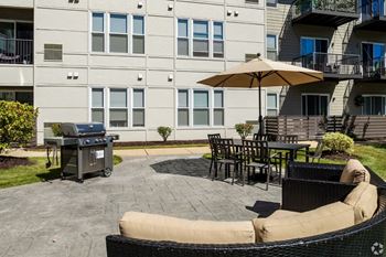 a patio with a grill and tables in front of an apartment building