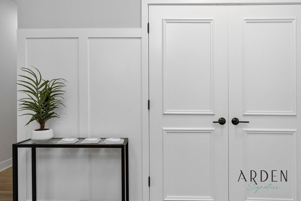 a white closet with white doors and a black table with a plant