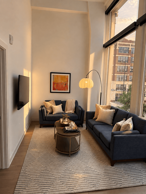 A living room with a dark blue couch, a coffee table, and a painting on the wall.