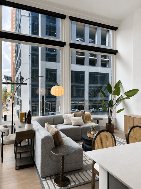 A living room with a grey couch and a large window.