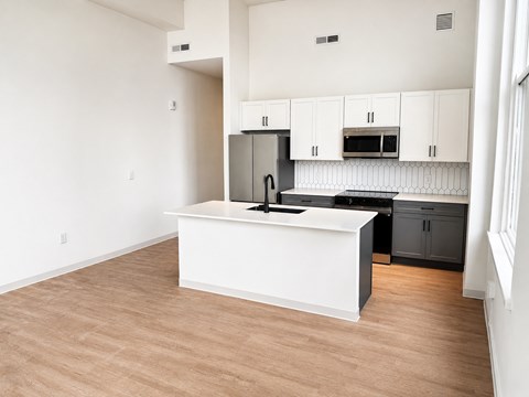 A kitchen with a white island and black countertop.