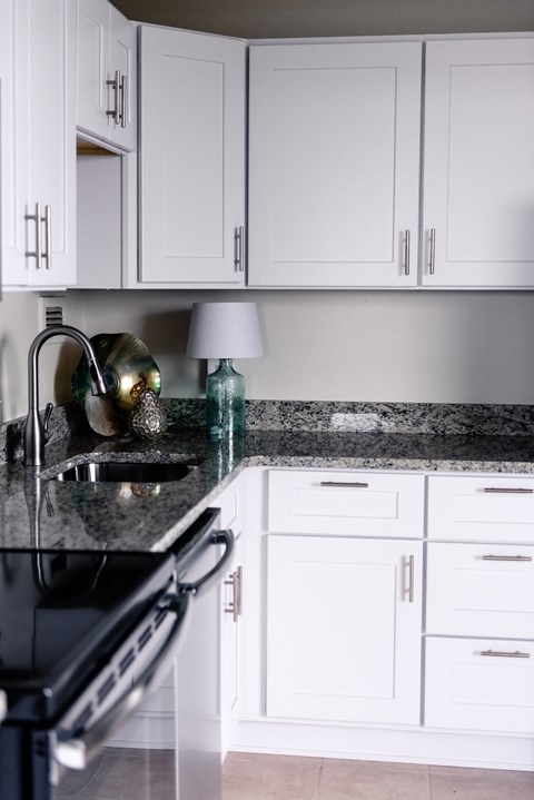 a white kitchen with marble counter tops and white cabinets at Hampton Plaza Apartments, Towson, MD