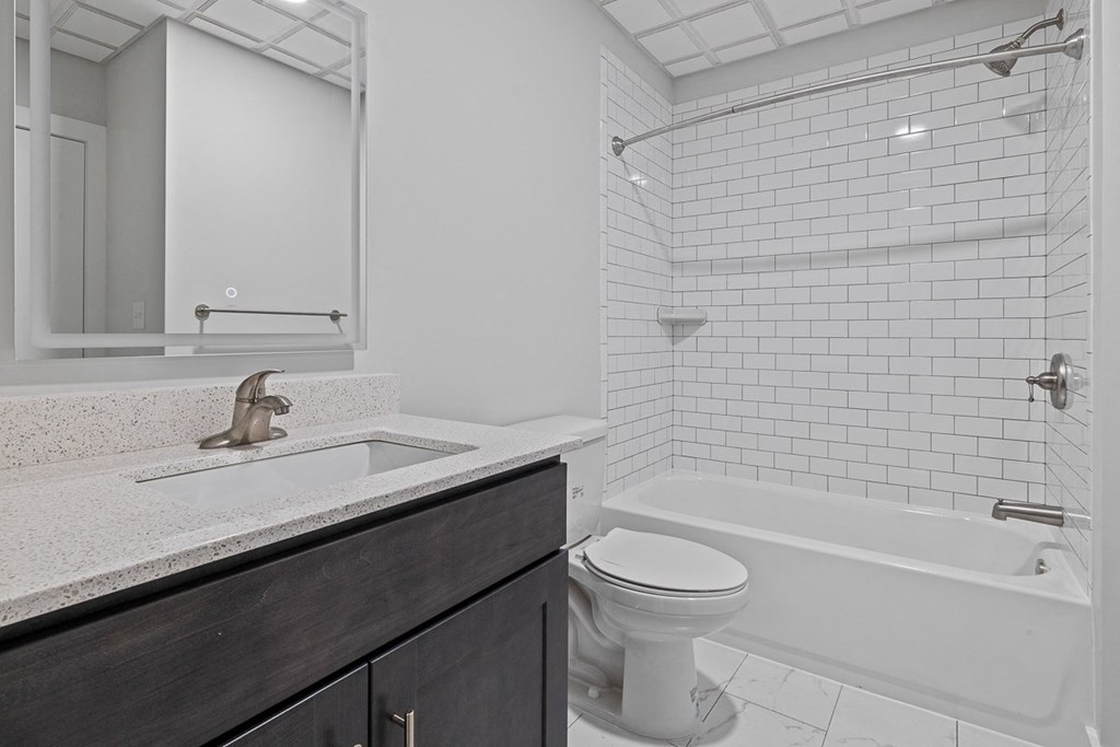 A white toilet sits next to a white bathtub in a bathroom at Hampton Plaza Apartments, Towson, MD