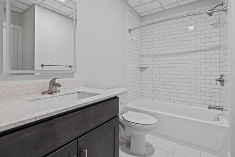 A white toilet sits next to a white bathtub in a bathroom at Hampton Plaza Apartments, Towson, MD