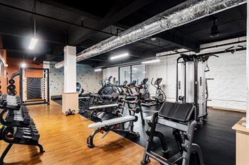 a gym with cardio equipment and weights on a wooden floor at Textile Apartments, Cincinnati, 45202