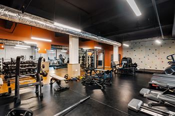 a gym with weights and cardio equipment and a rock climbing wall at Textile Apartments, Cincinnati, OH