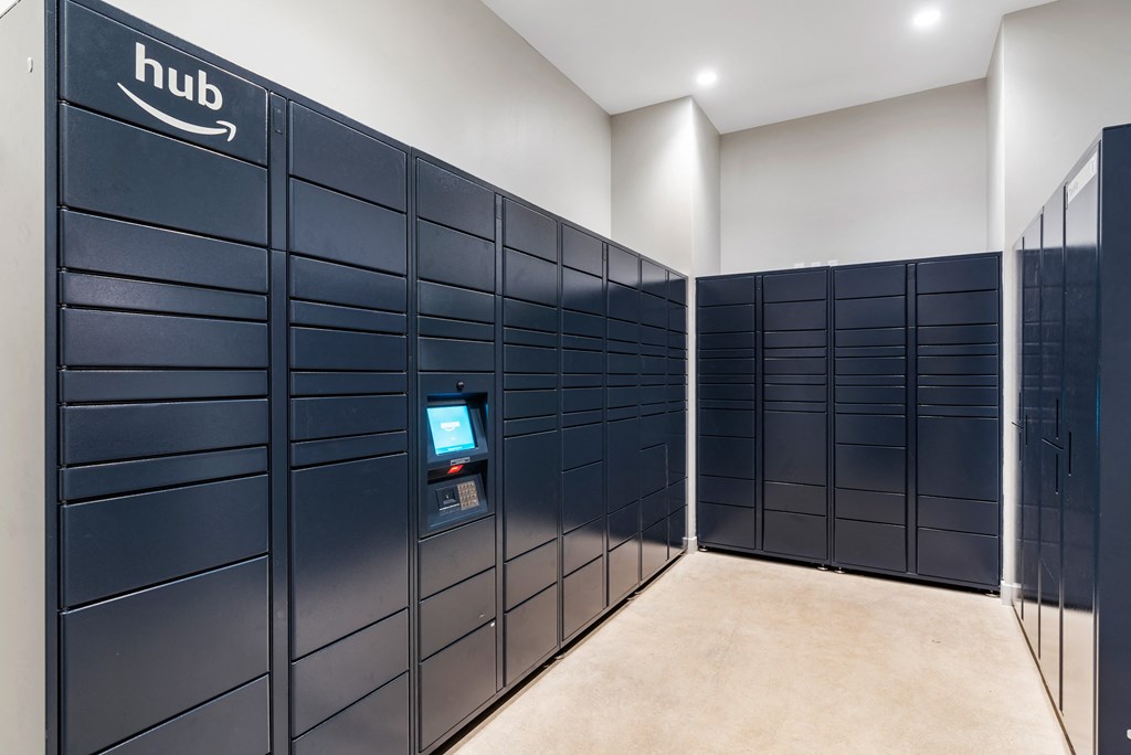 a row of navy blue parcel lockers in a room with a computer in the middle at Textile Apartments, Cincinnati, OH, 45202