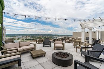 a roof top patio with couches and chairs and a fire pit at Textile Apartments, Ohio, 45202