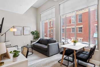 a living room with large windows and a couch and a table at Textile Apartments, Ohio, 45202
