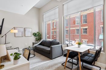 a living room with large windows and a couch and a table at Textile Apartments, Cincinnati, Ohio