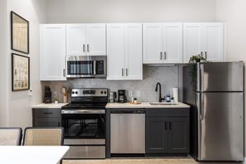 a kitchen with stainless steel appliances and white cabinets at Textile Apartments, Cincinnati, OH