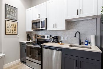 an apartment kitchen with stainless steel appliances and white cabinets at Textile Apartments, Cincinnati