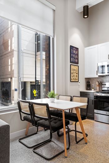 a dining room with a large window and a table with black chairs at Textile Apartments, Ohio