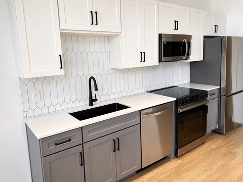 A kitchen with white cabinets and a black sink.