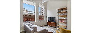 a living room with a couch and a tv and a window