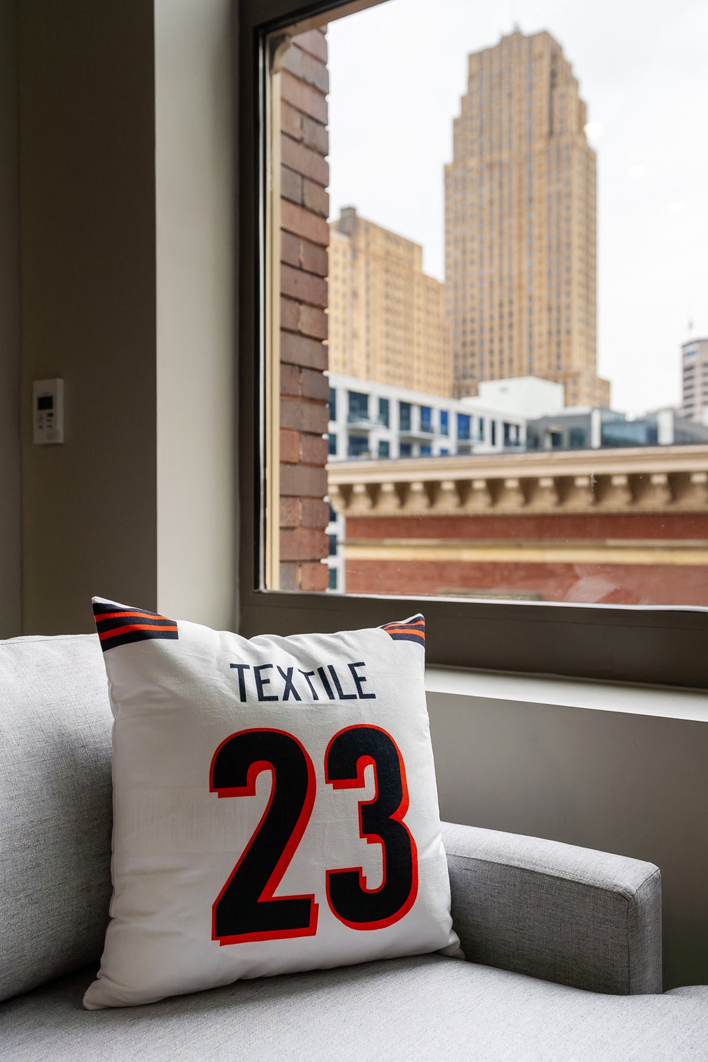 a pillow with the number 23 on it sitting on a couch next to a window at Textile Apartments, Cincinnati, Ohio