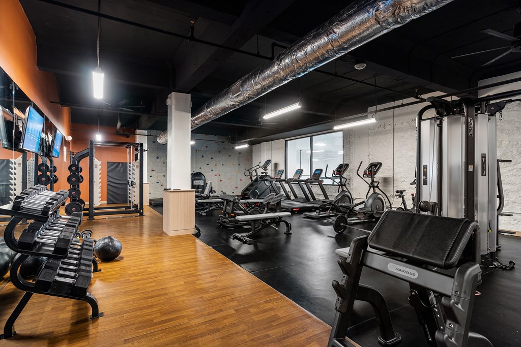 a gym with cardio machines and weights on a wooden floor at Textile Apartments, Cincinnati, Ohio