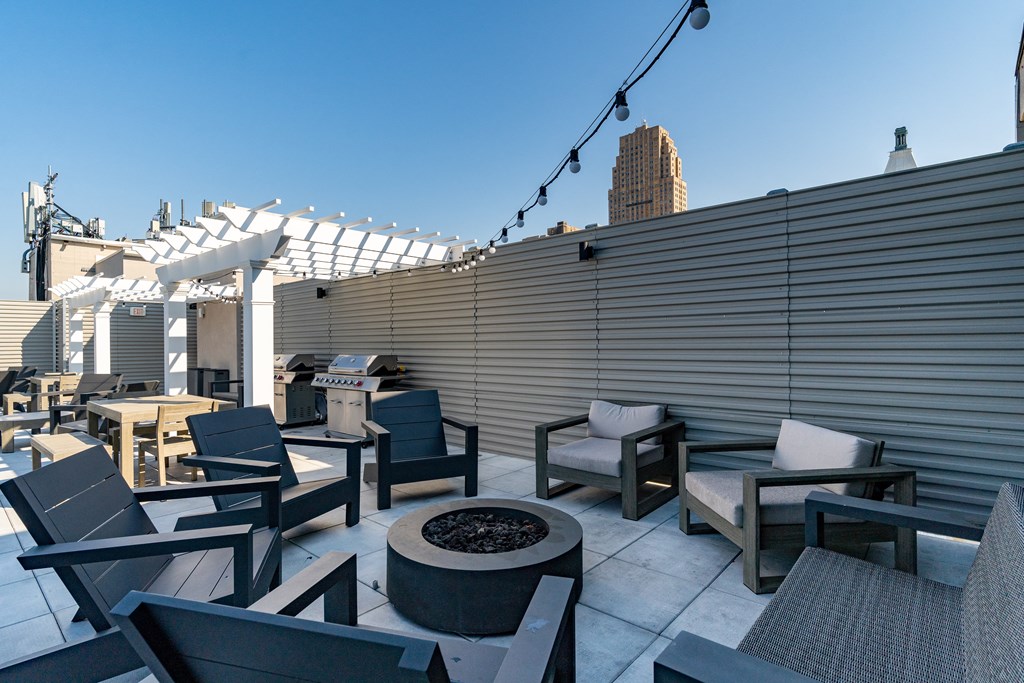 a roof top patio with chairs and tables and a fire pit at Textile Apartments, Ohio