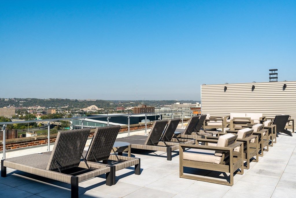a row of lounge chairs on a roof top overlooking a city at Textile Apartments, Cincinnati