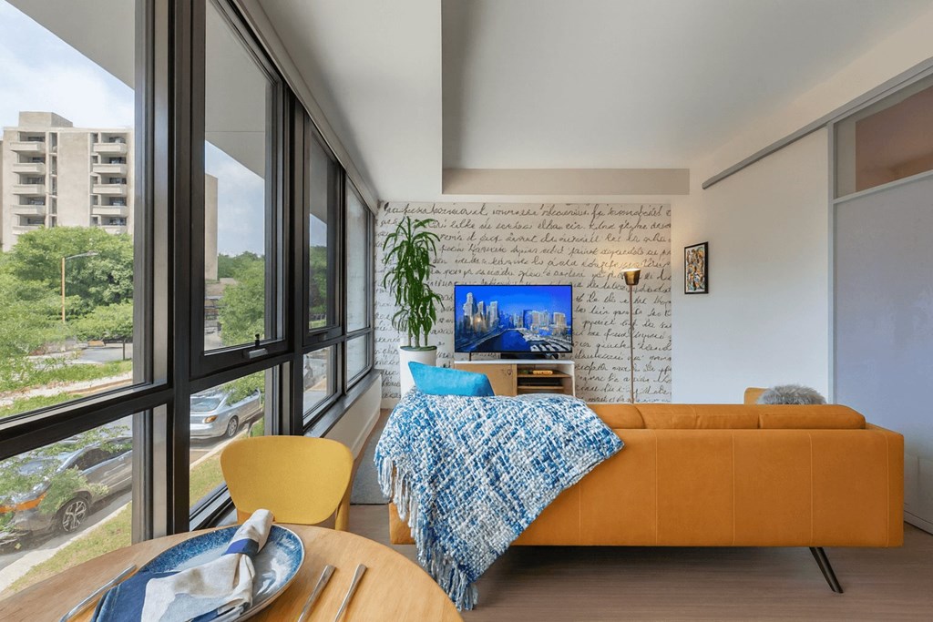 A bedroom with a bed, a chair, and a table with a plate on it.