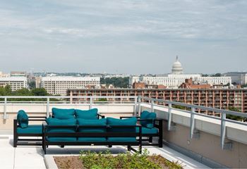 Two green couches on a balcony overlooking the city.