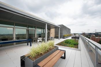 A rooftop patio with a bench and a planter box.