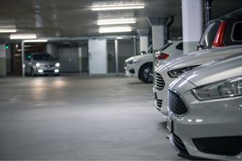 A row of cars are parked in a dimly lit parking garage.