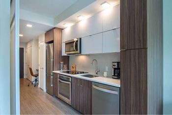 A modern kitchen with dark wood cabinets and stainless steel appliances.
