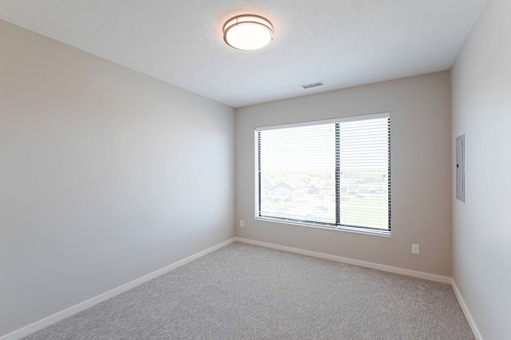 an empty room with a large window and white walls