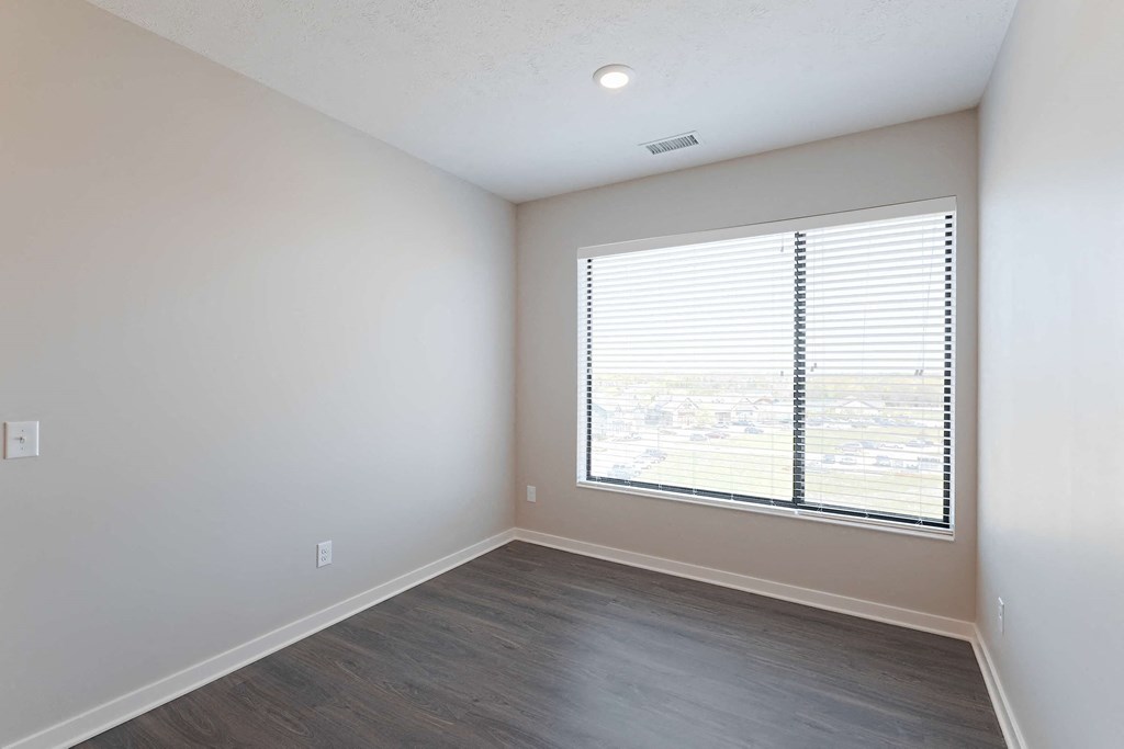 an empty living room with a large window and wood floors