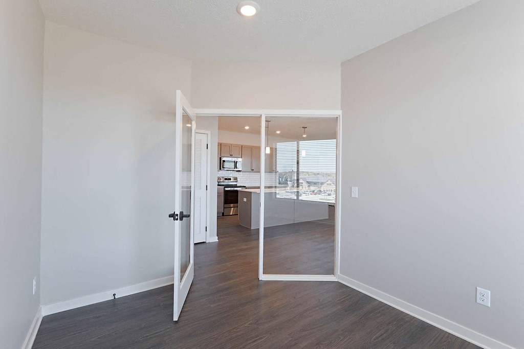 a living room and kitchen with white walls and wood floors