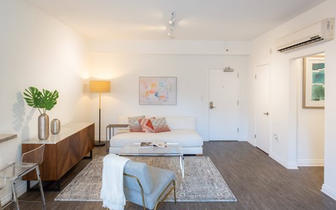 A living room with a white couch, a wooden table, and a white chair.