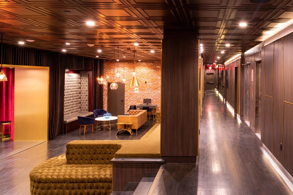 Lobby space with brick and wooden walls, wooden flooring, and brown furniture