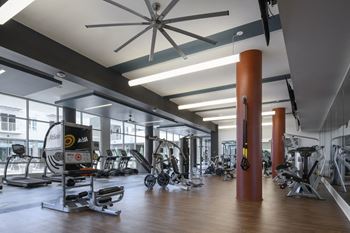 A gym with a variety of equipment and a ceiling fan.