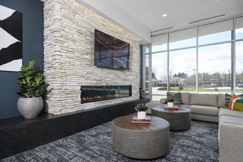 A modern living room with a stone fireplace and a large window.