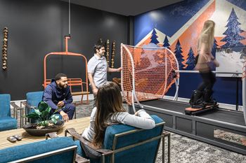 A woman is sitting on a blue chair in a room with a mural of a snowy mountain scene on the wall.