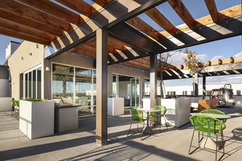 A patio with a white table and green chairs under a wooden pergola.