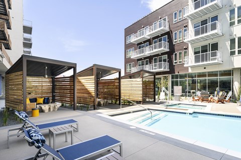 a swimming pool with chairs and tables in front of an apartment building