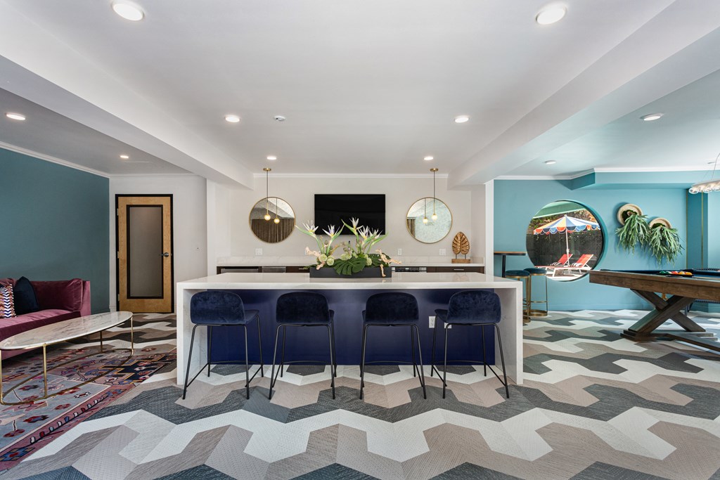 a kitchen with a bar and blue chairs and a rug