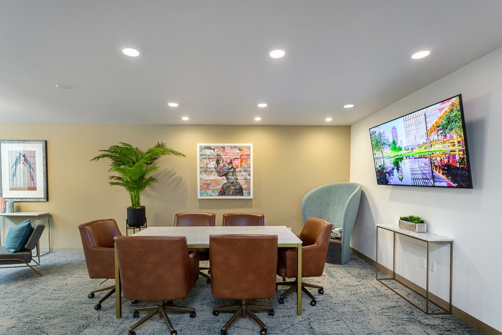 a conference room with a table and chairs and a tv on the wall
