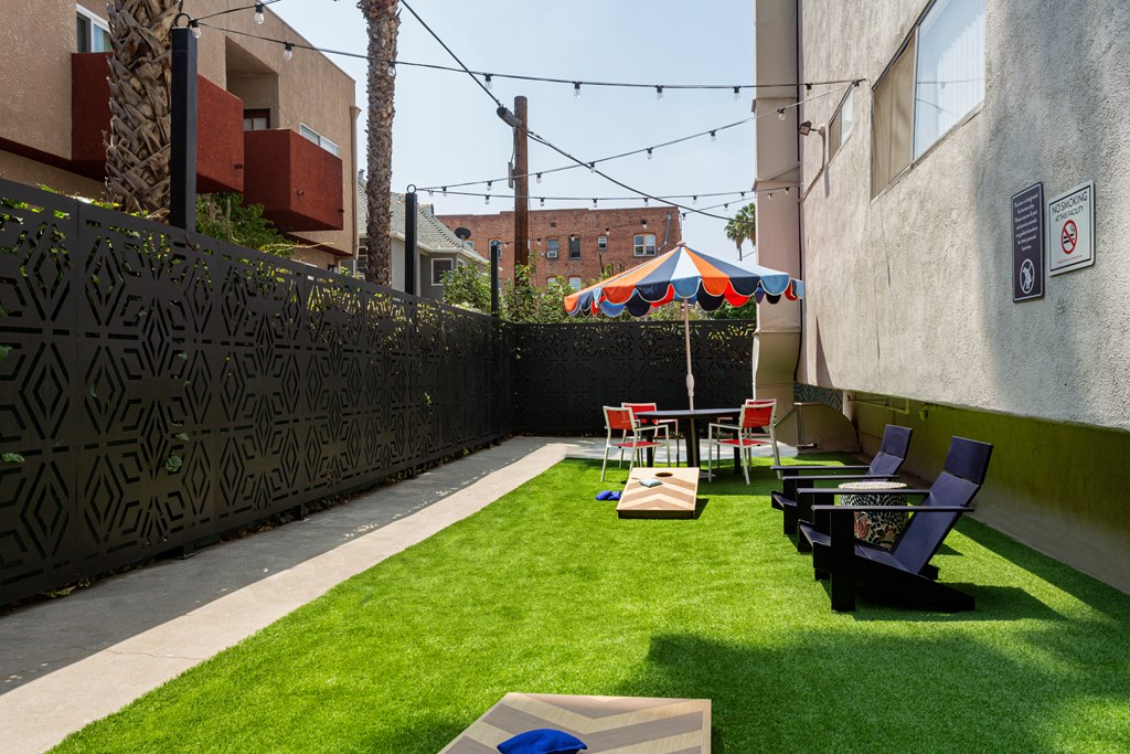 a backyard patio with tables and chairs and grass