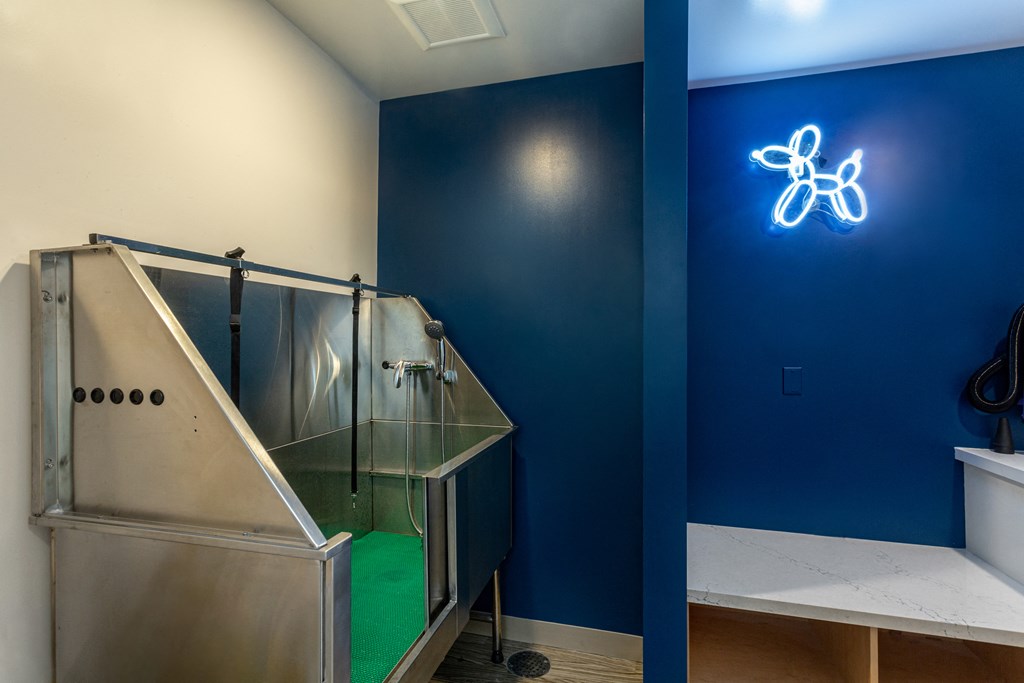 a room with a glass incubator and a blue wall with a neon atom sign