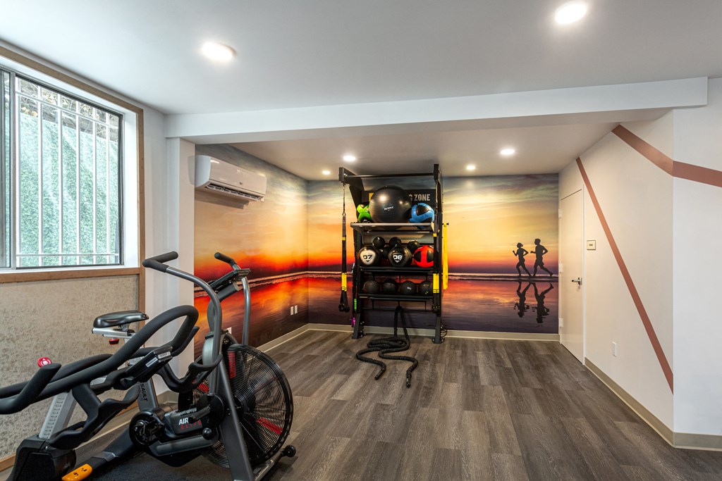 a workout room with bikes and a wall mural