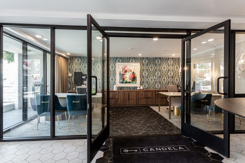 a lobby with glass doors and tables and chairs and a rug